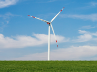 Ein Windrad steht in der Landschaft.